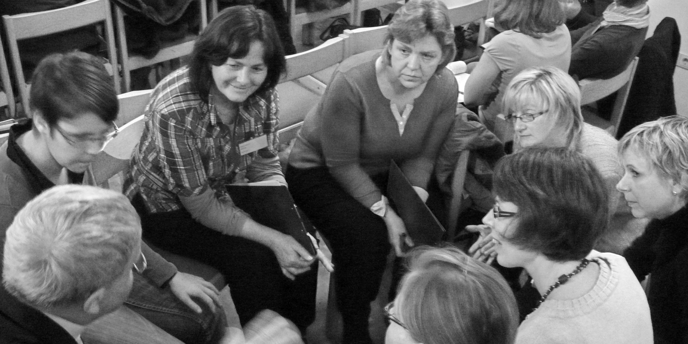 acht Menschen sitzen eng im Kreis und unterhalten sich angeregt