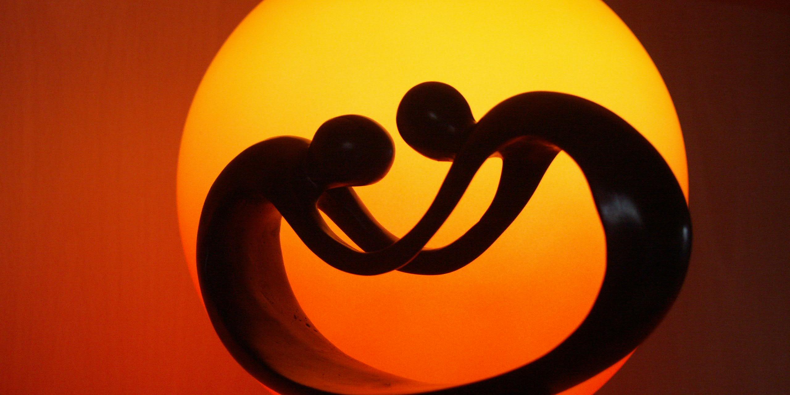 eine Tischlampe aus einer Skulptur von zwei Figuren in gebeugter Haltung, die sich an den Händen halten