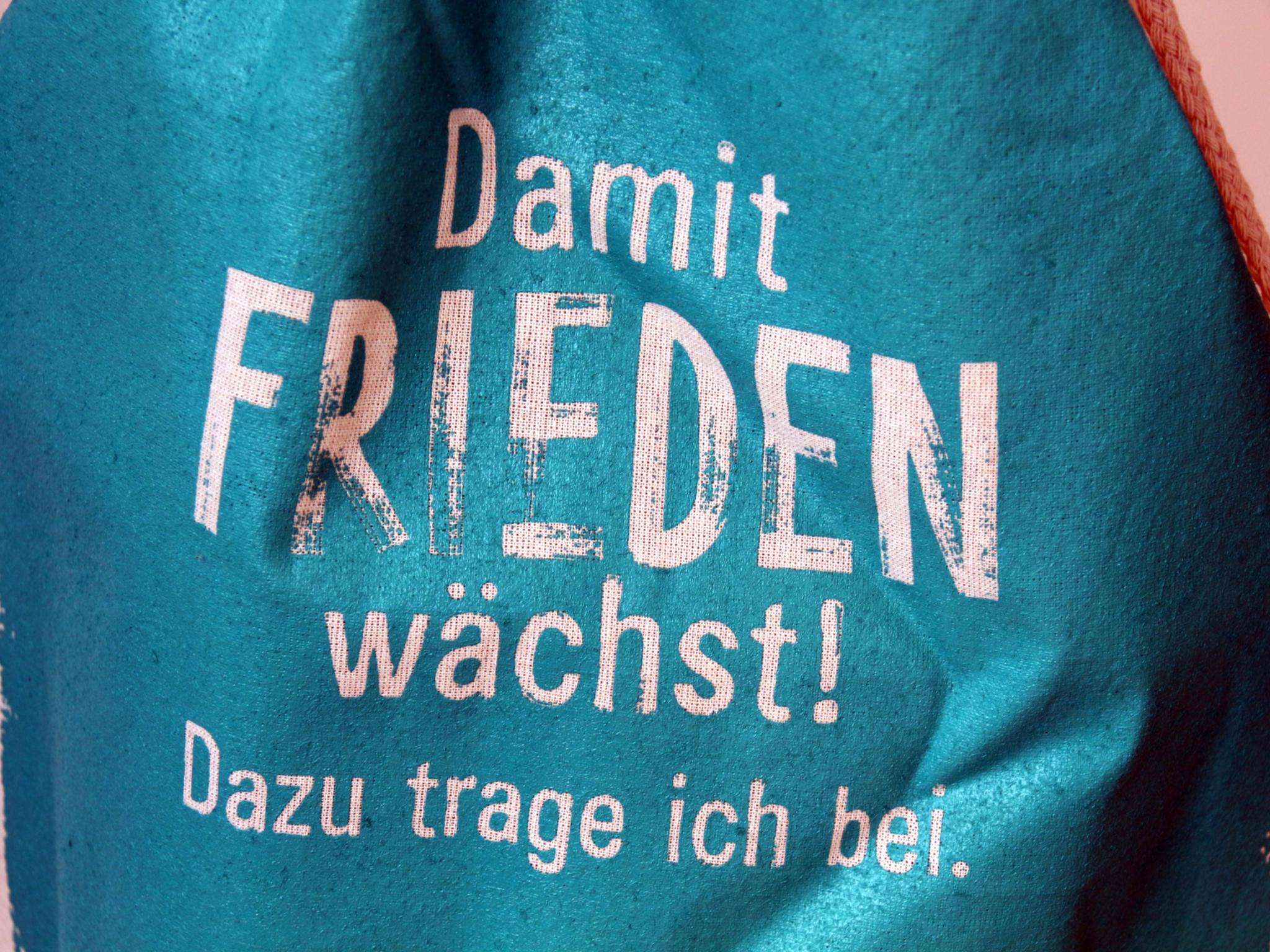 Türkisfarbene Tasche mit dem Schriftzug: Damit Frieden wächst! Dazu trage ich bei.