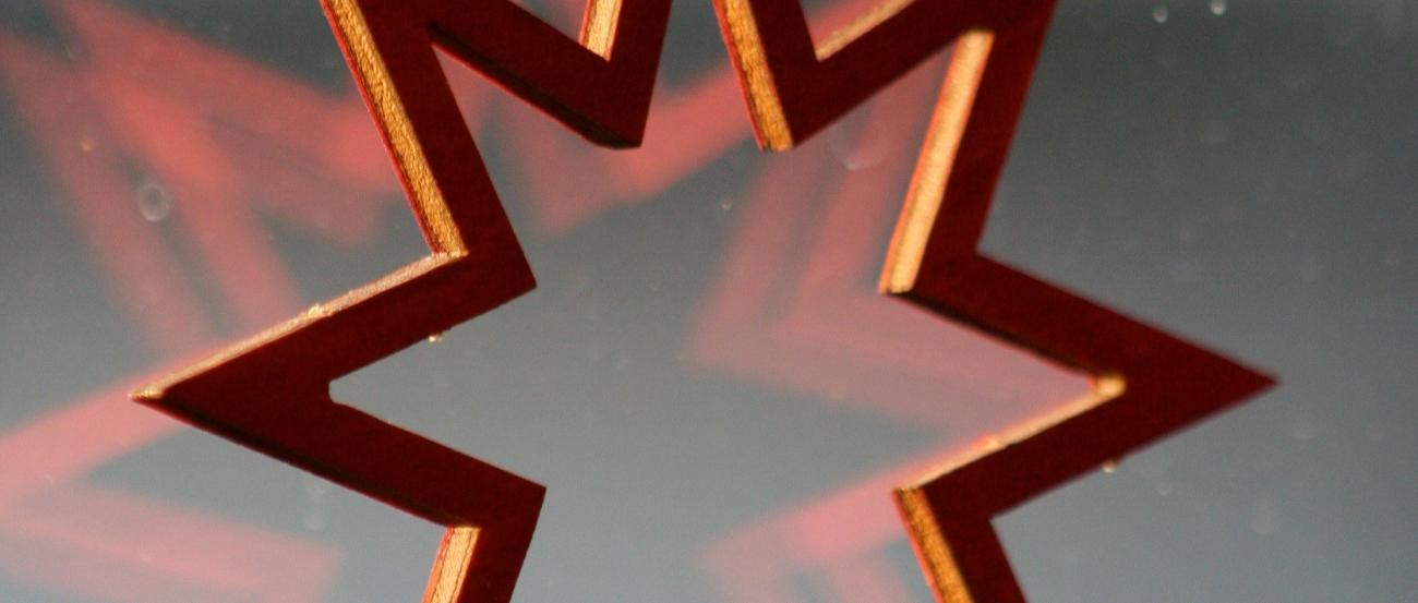 ein Holzstern am Fenster, die Silhouette spiegelt sich leicht