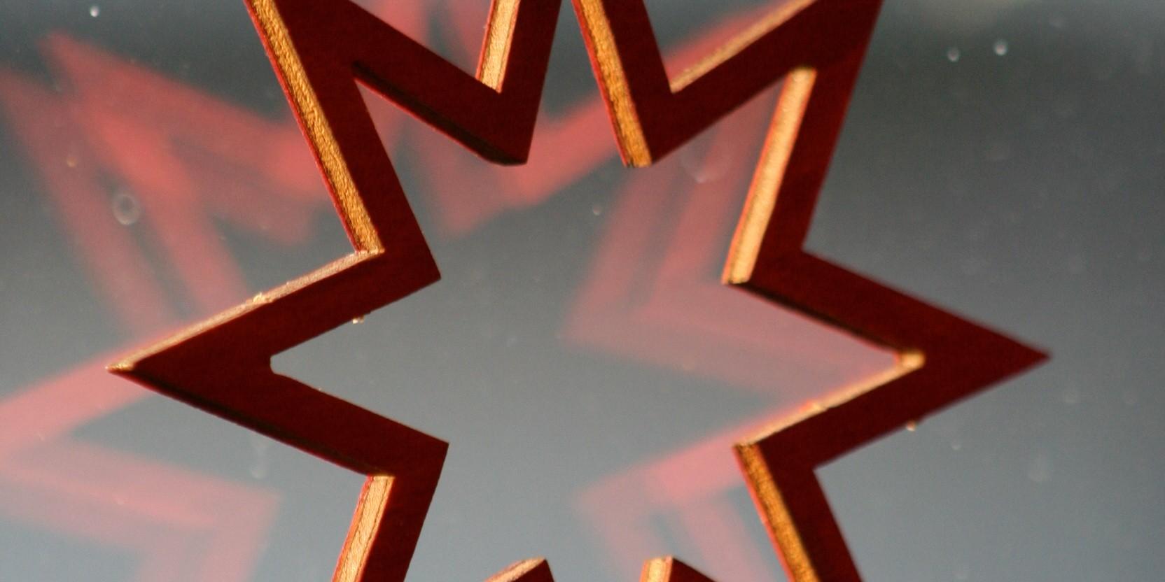 ein Holzstern am Fenster, die Silhouette spiegelt sich leicht