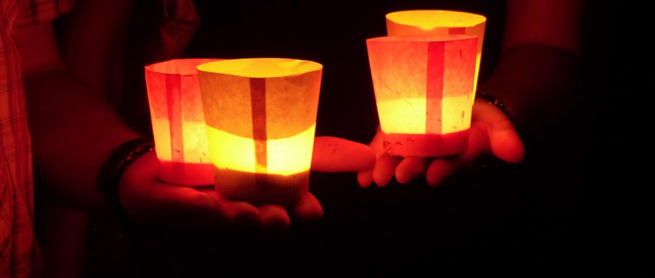 4 Gläser, beklebt mit Transparentpapier werden auf auf 2 Händen gehalten