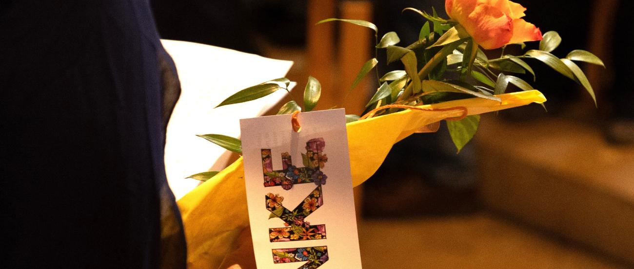 Junge Frau hält Blumen und ein Schild mit 'Danke' in der Hand