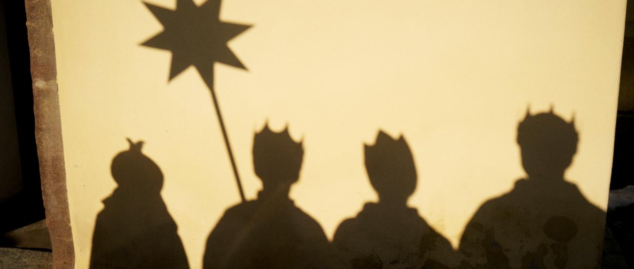 4 Sternsinger mit Stern als Silhouette hinter einem Tuch