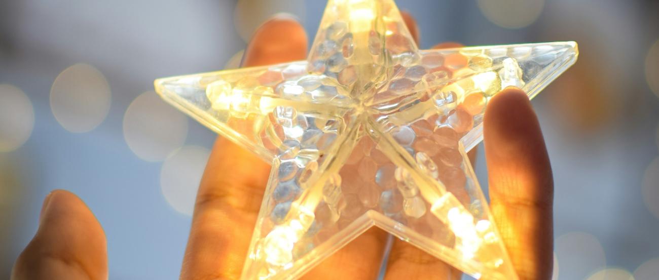 eine offene Hand hält einen beleuchteten Stern einer Lichterkette