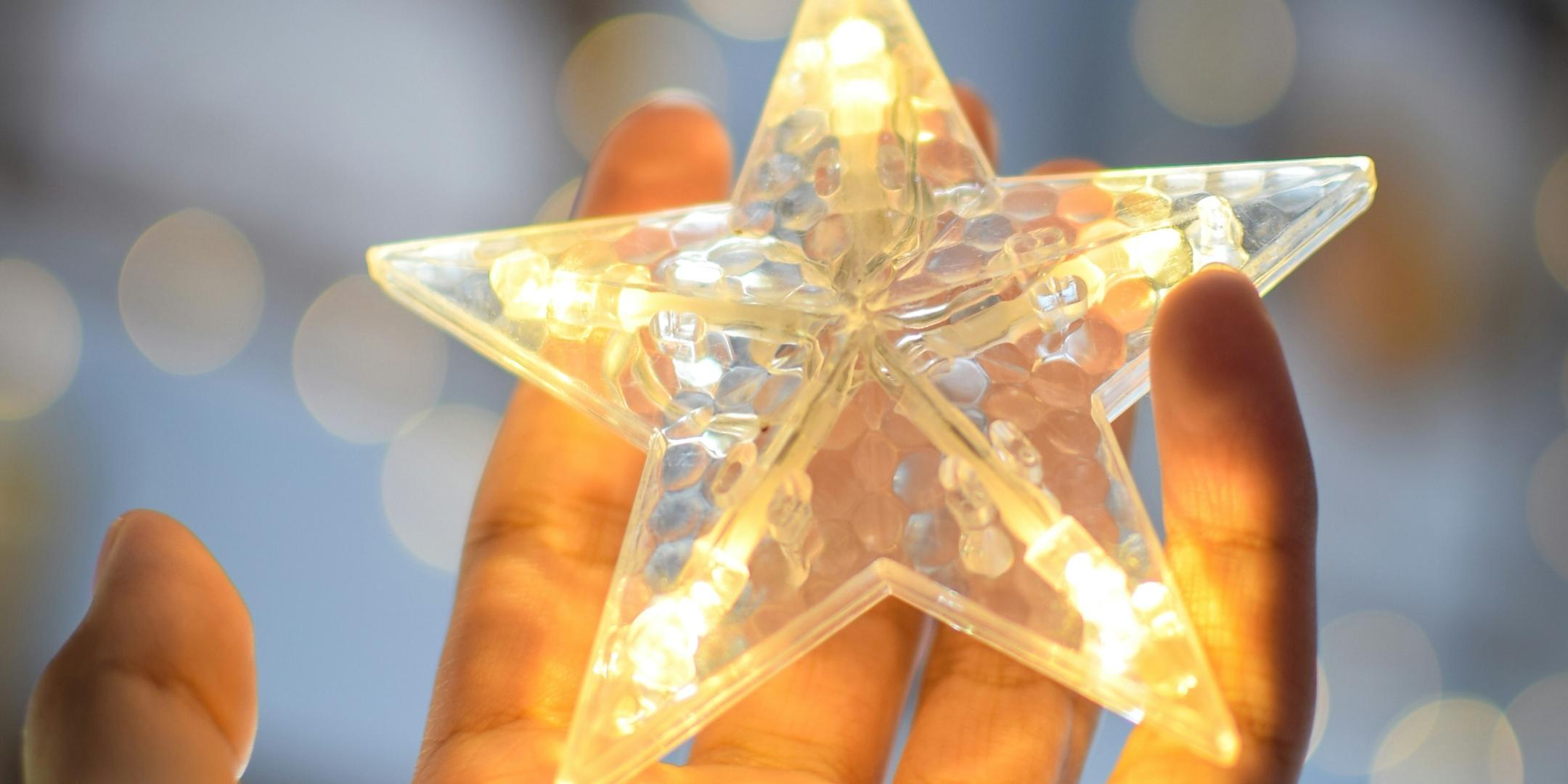 eine offene Hand hält einen beleuchteten Stern einer Lichterkette