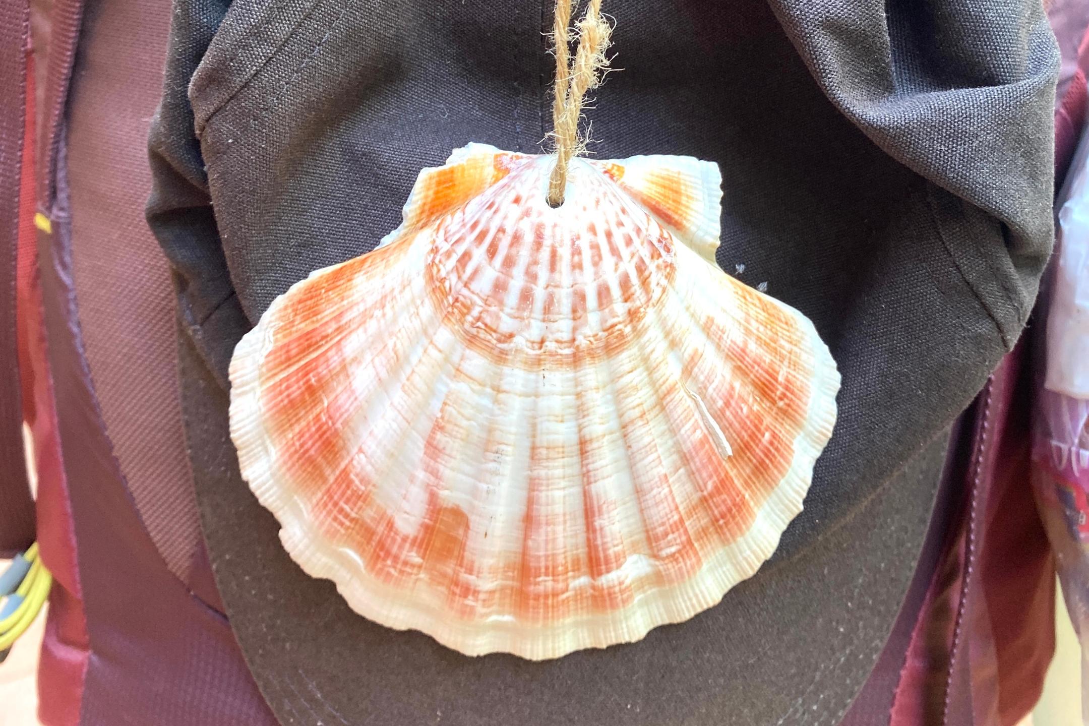 am Rucksack hängen Pilgermütze und Pilgerkopfebedeckung