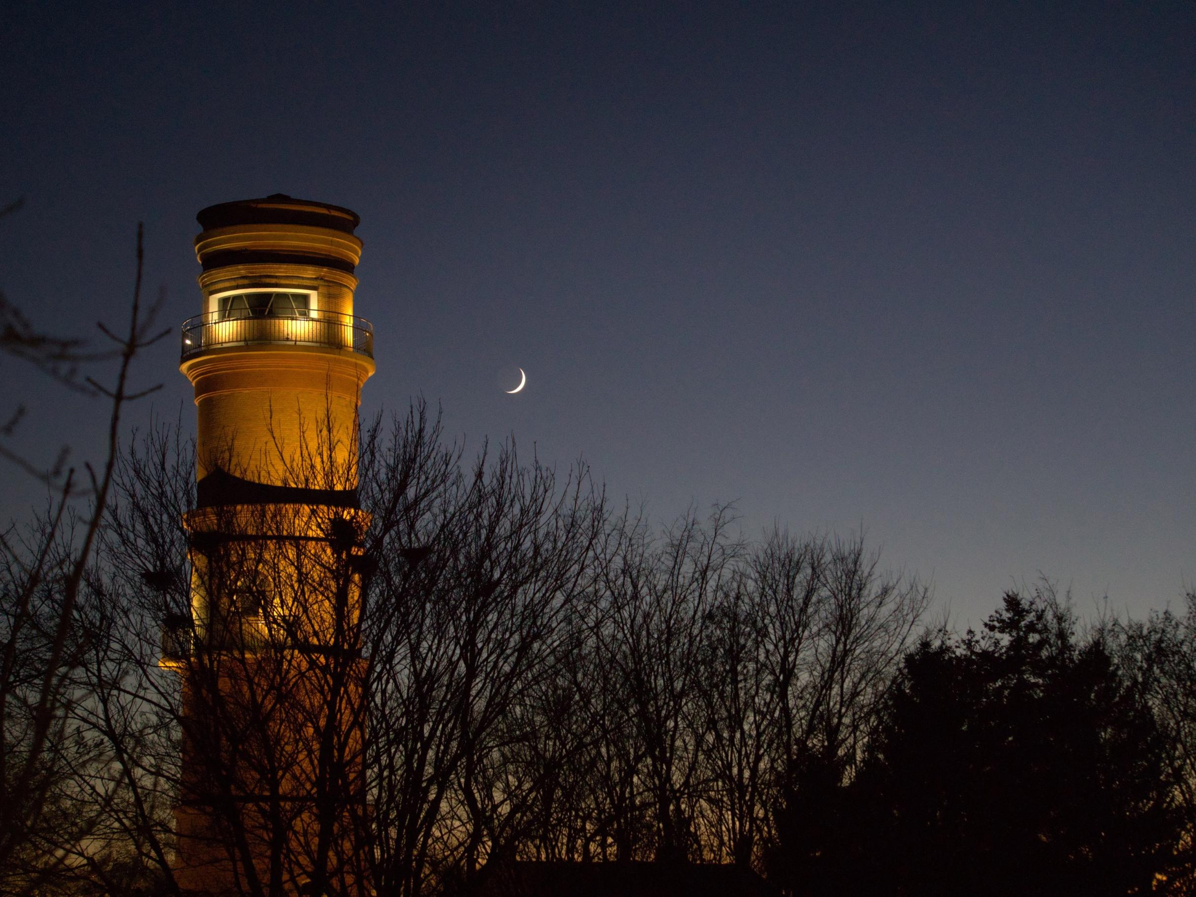 ein angeleuchteter Leuchtturm in der Abenddämmerung