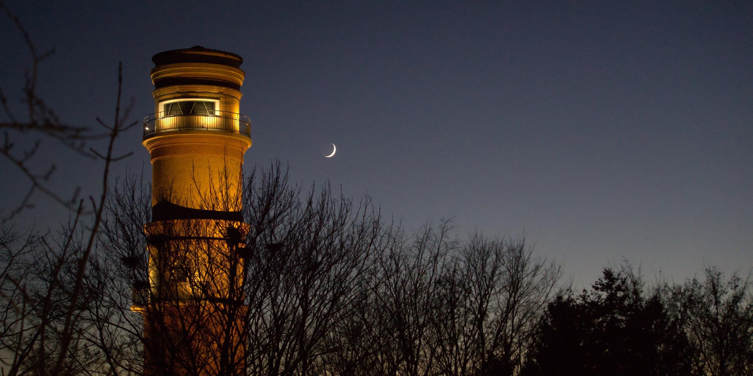ein angeleuchteter Leuchtturm in der Abenddämmerung