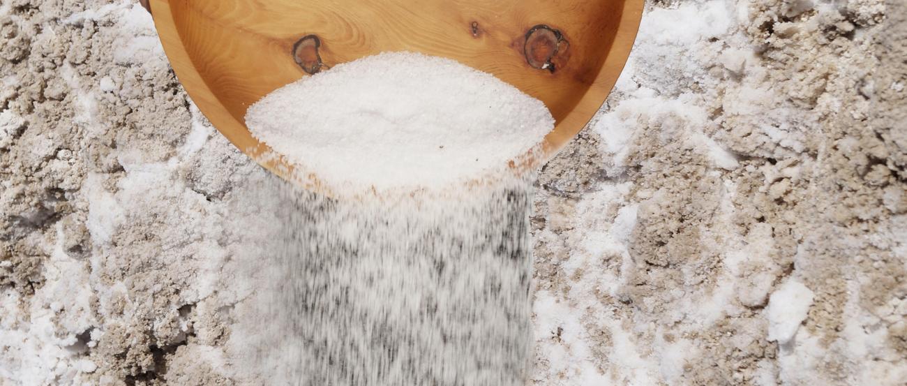 Salz wird aus einer Holzschüssel auf die Erde gestreut