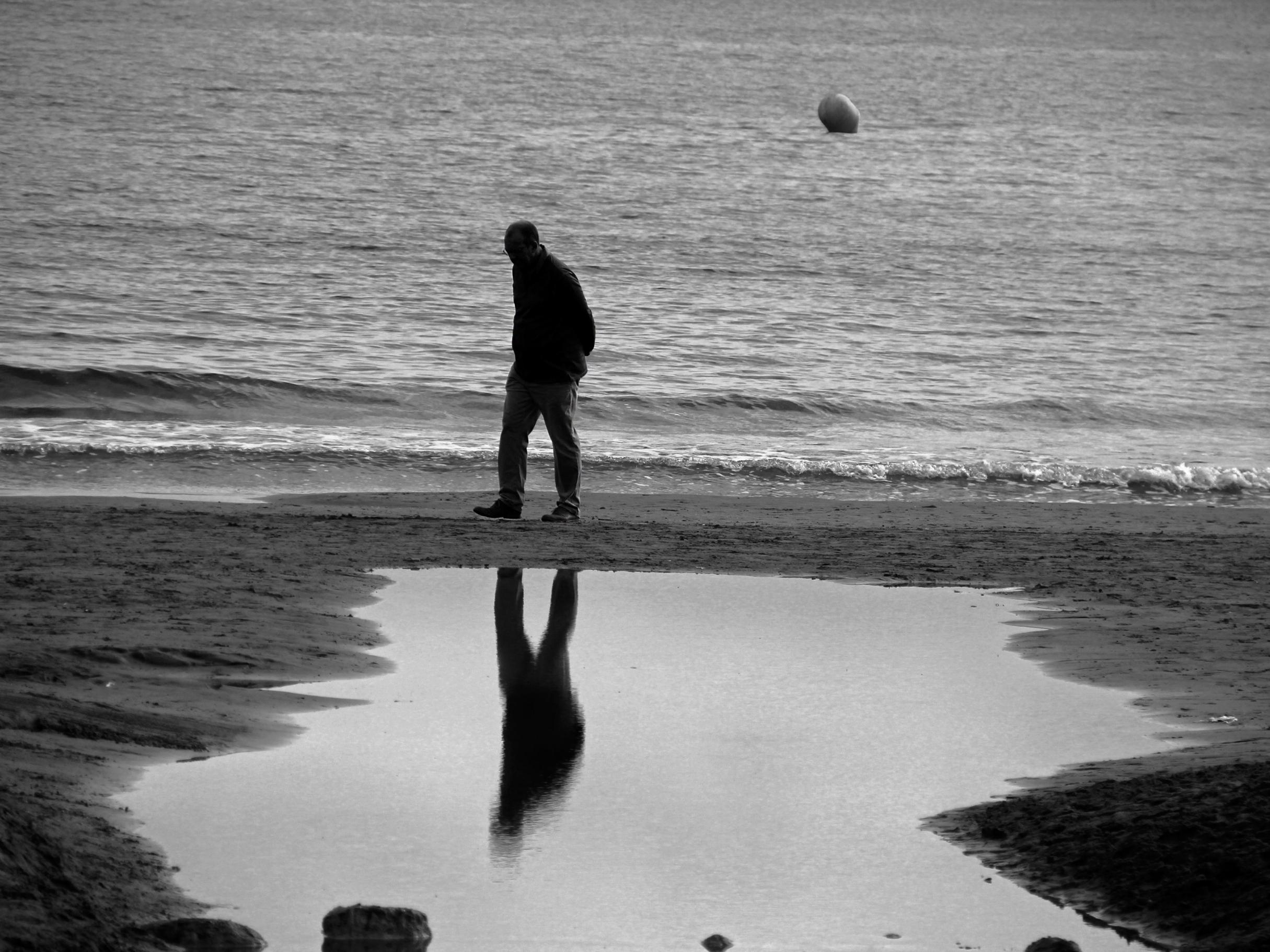 ein Mann geht allein am Strand entlang