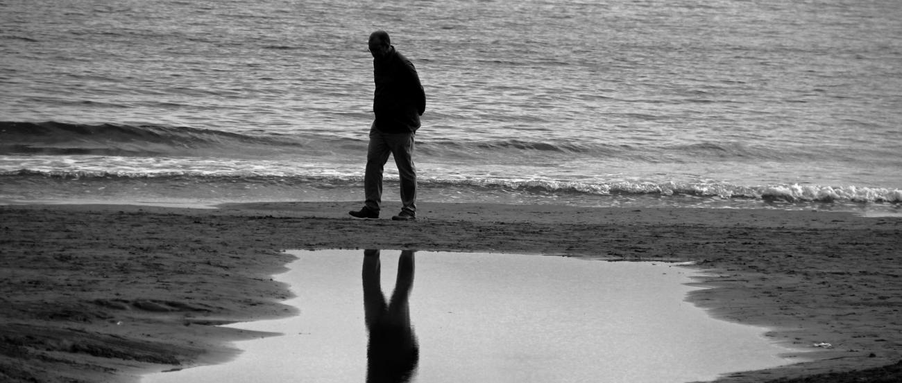 ein Mann geht allein am Strand entlang