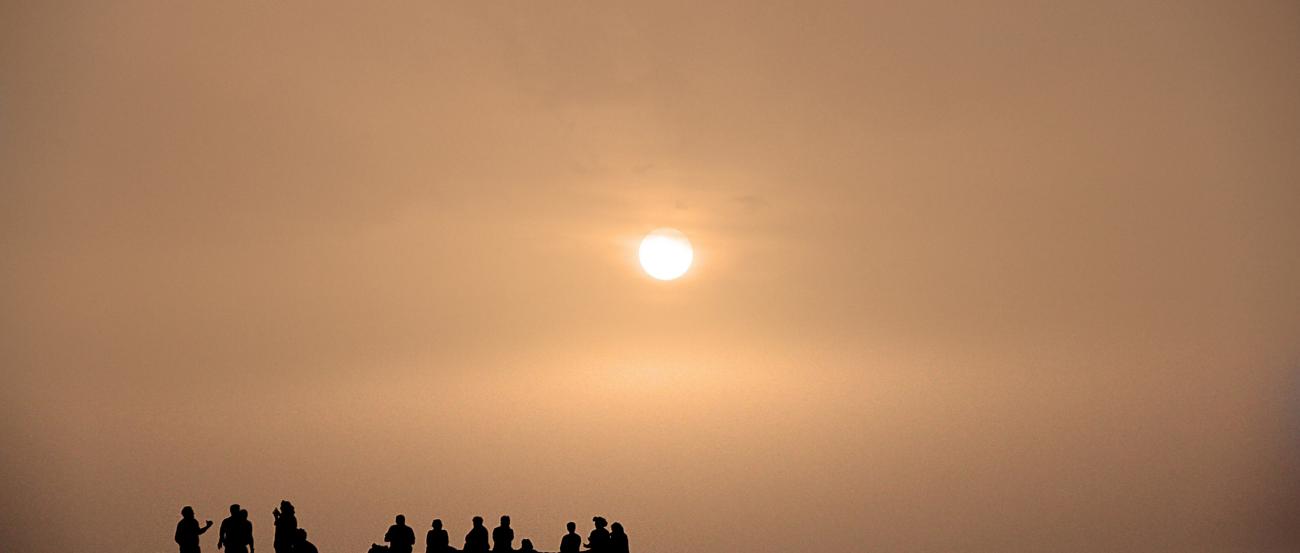 Sonnenuntergang, davor ein Hügel mit Menschen