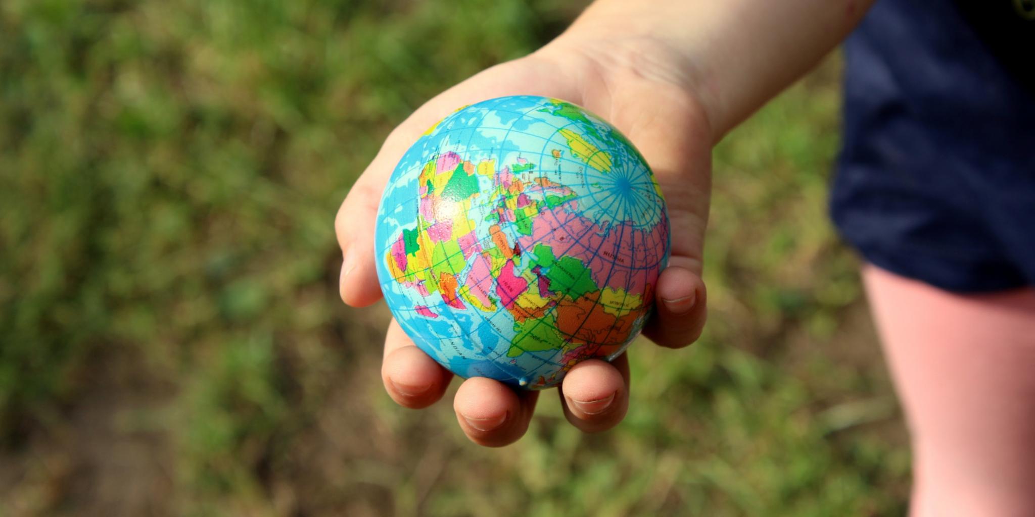 ein Kind hält einen Erdkugelball in seiner Hand